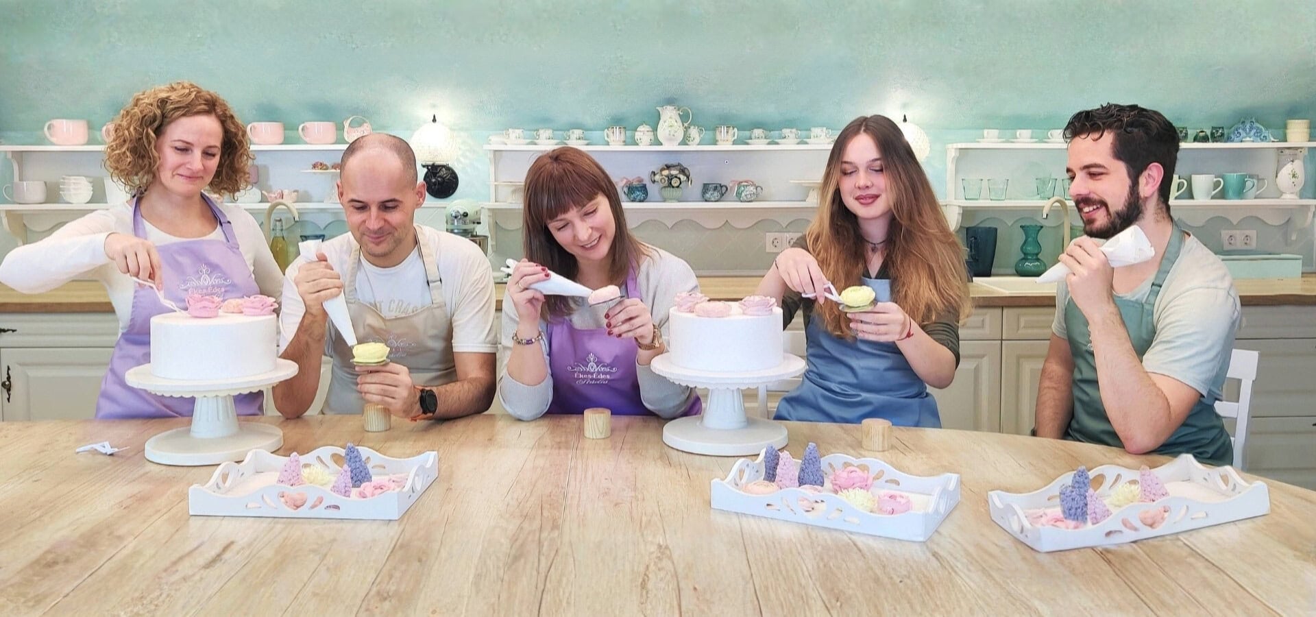 Résztvevők tortát díszítenek krém virágokkal az Ékes-Édes Stúdió tanfolyamán.