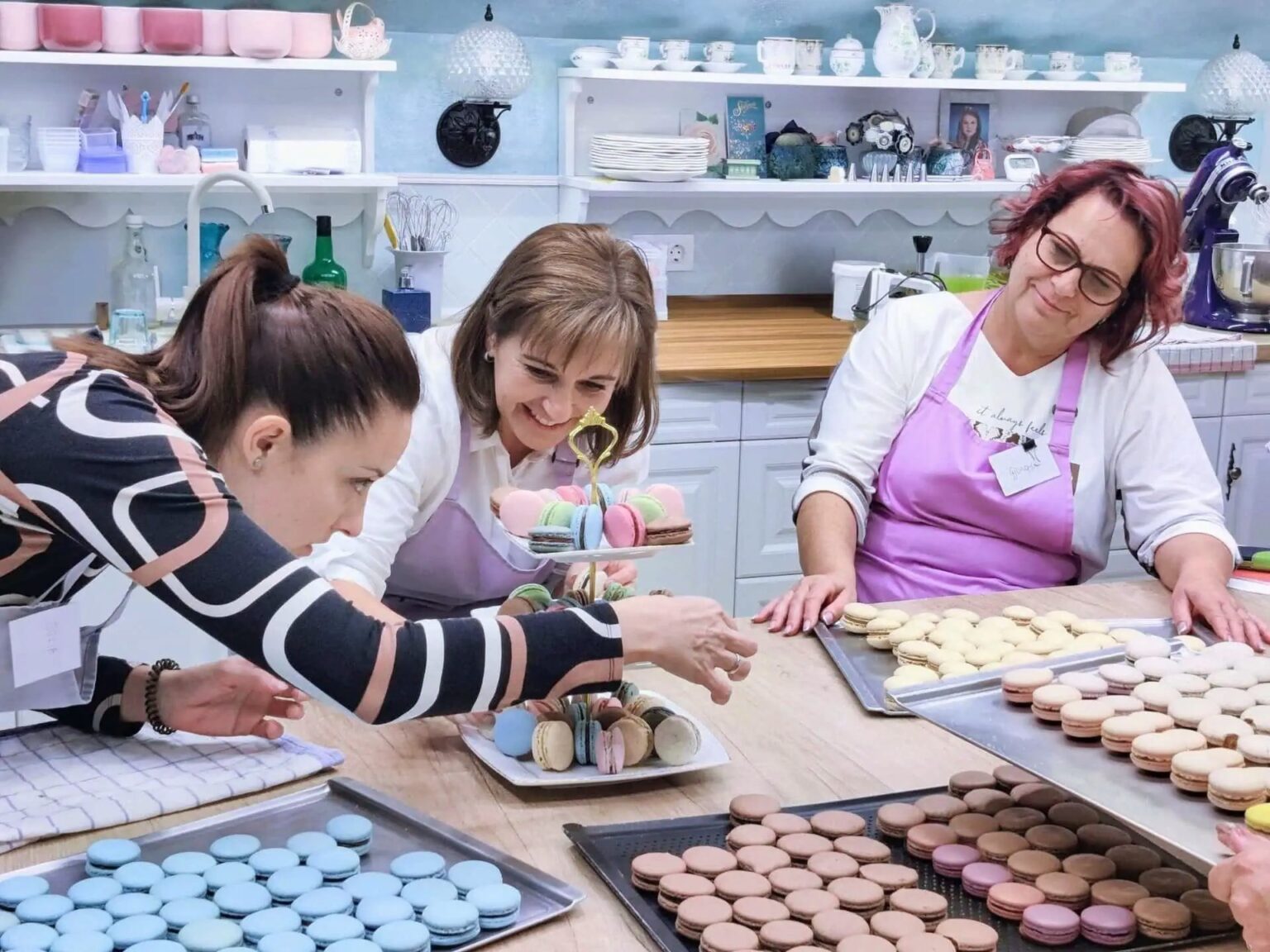 Cukrász tanfolyam résztvevői az elkészült macaronokat emeletes tálalóra teszik fel.