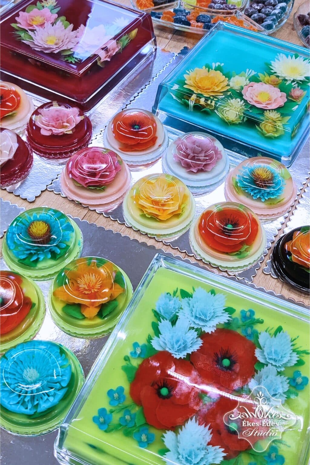 A tanfolyamon készült kisebb virágos desszertek és a tanulók tortái fotózáshoz egymás mellé rendezve