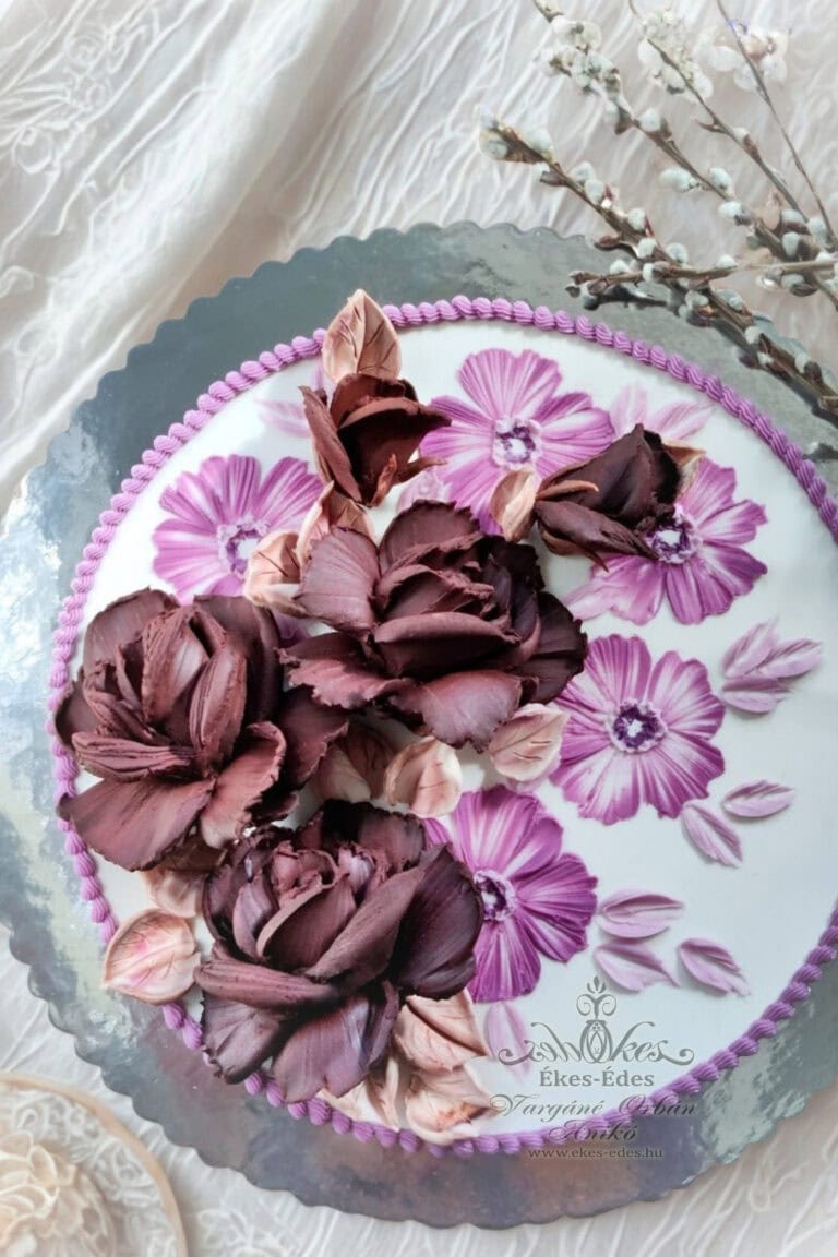 Ékes-Édes Stúdió tortadíszítés tanfolyamán készült csokoládéval és kézi festéssel: étcsokoládéból nagy méretű rózsák és festett 2D rózsaszín mályvák egyszerű tortán.