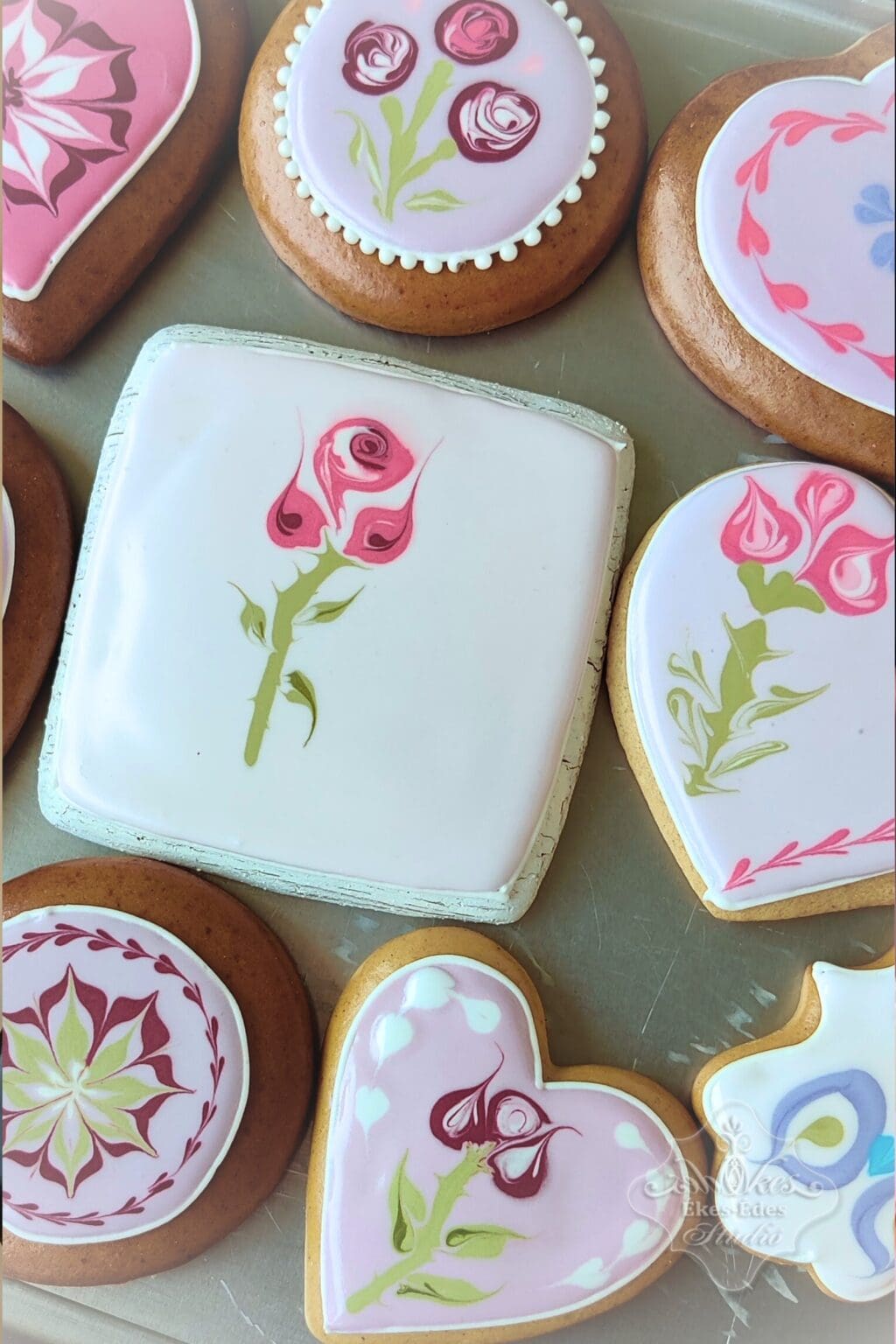 Ékes-Édes Stúdió cukormázas tanfolyamán finom díszített sütemények színezett terülőmázzal kialakított virág és szív mintákkal.