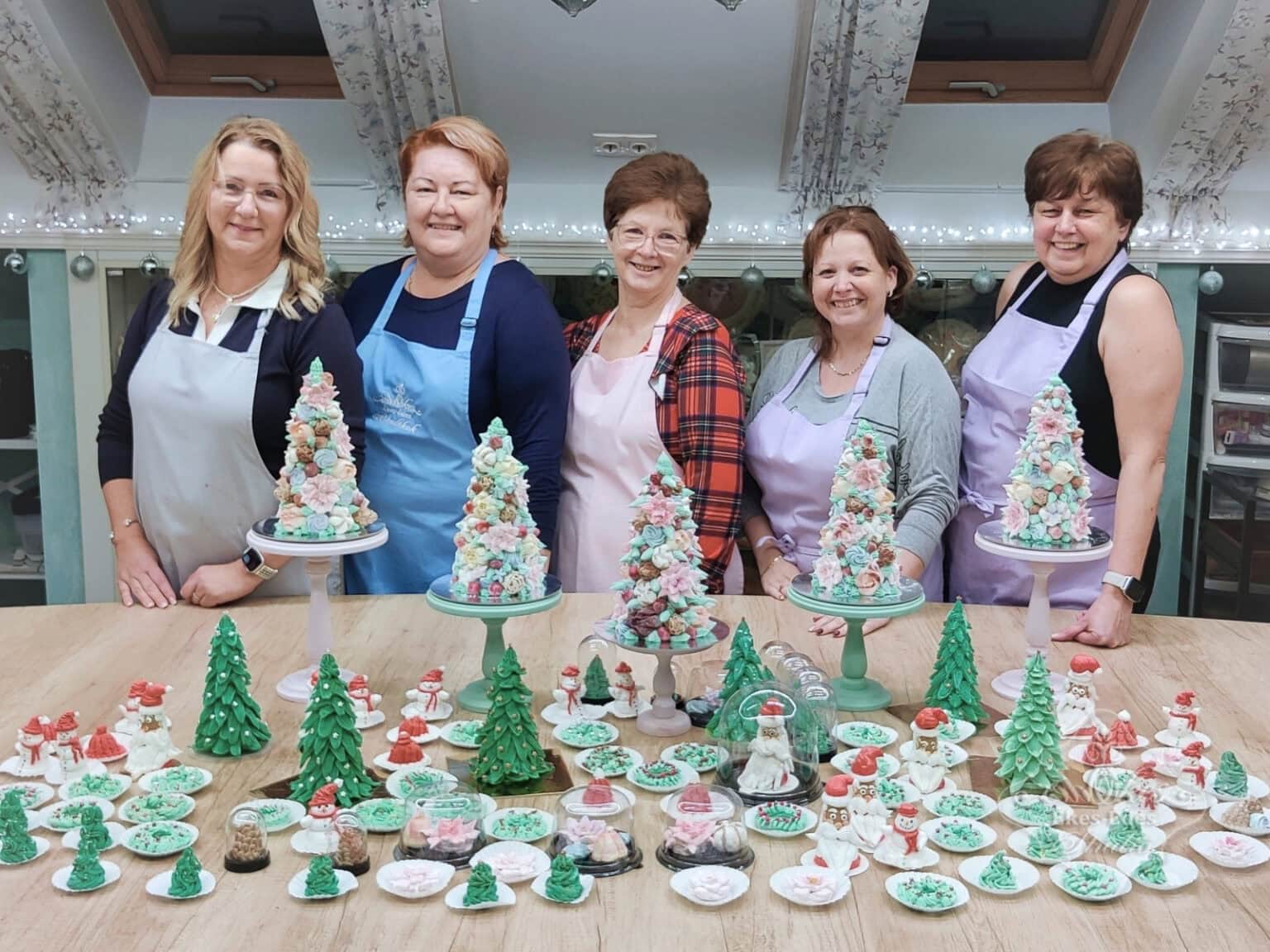 Ékes-Édes Stúdió karácsonyi pillecukor készítő tanfolyam végén csoportkép mosolygós emberekkel és a rengeteg elkészült termékkel az asztalon.