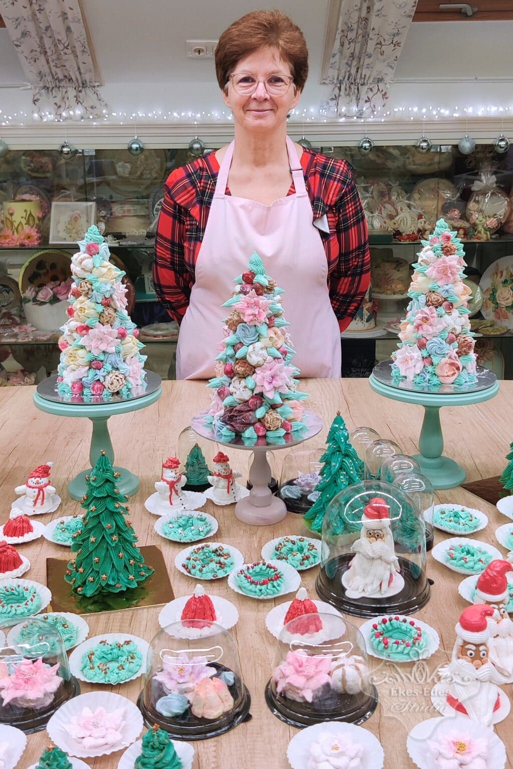 Ékes-Édes Stúdió karácsonyi pillecukor tanfolyama végén a termékektől roskadó asztal és mögötte egy vidám és elégedett résztvevő mosolyog.