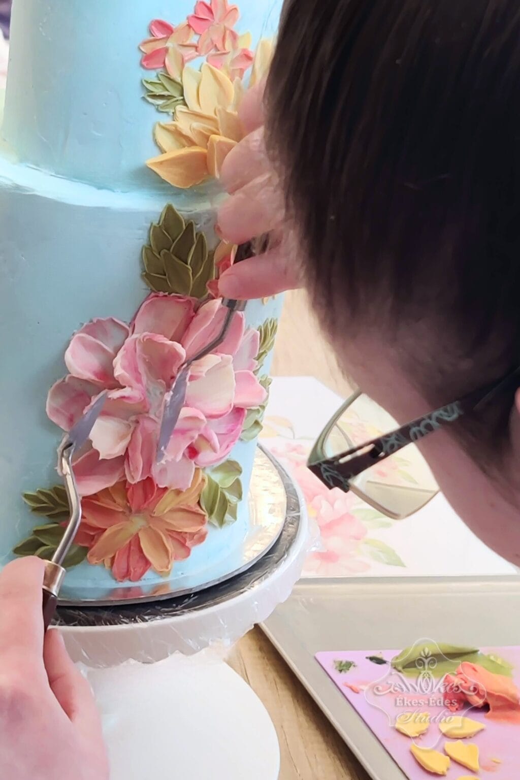 Csokoládés dekorációt készít egy résztvevő festőkésekkel, közeli kép – Ékes-Édes Stúdió, tortadíszítő tanfolyam