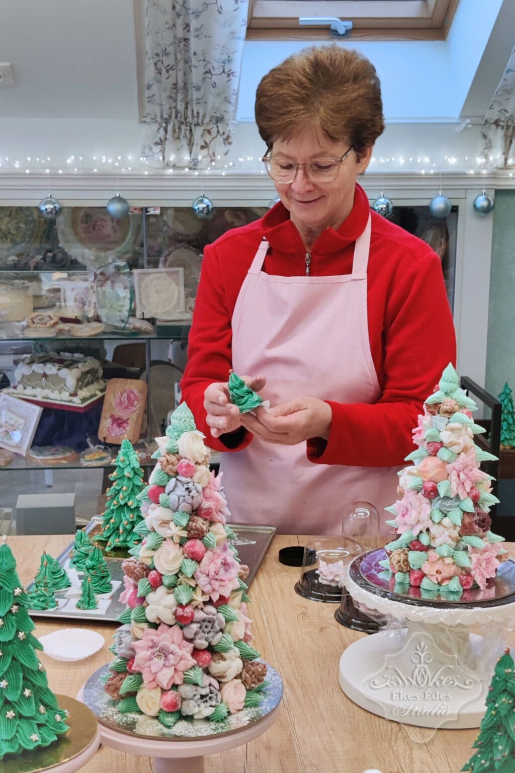 Karácsonyi dekoráció készítése szorgalmas résztvevővel, aki színes pillecukrokat és díszeket formál.