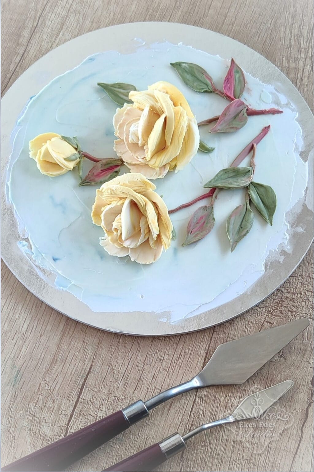 Virágos torta dekoráció gyakorlása táblán, előtérben a festőkésekkel – Ékes-Édes Stúdió, csokoládés tortadíszítő tanfolyam