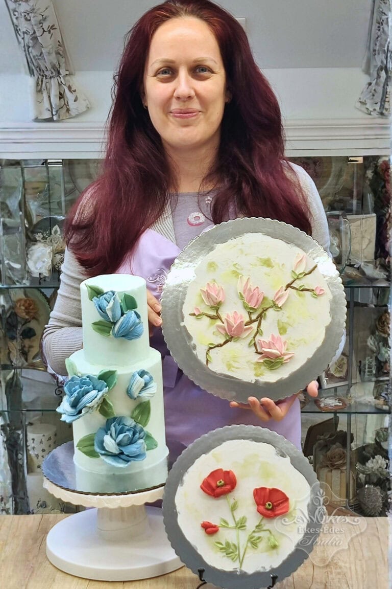 Tanfolyam résztvevője örömmel mutatja a csokoládéval díszített tortáját és késsel és csokoládéval festett változatos virágmotívumokkal készített gyakorló kompozícióit – Ékes-Édes Stúdió, tortadíszítő tanfolyam vége