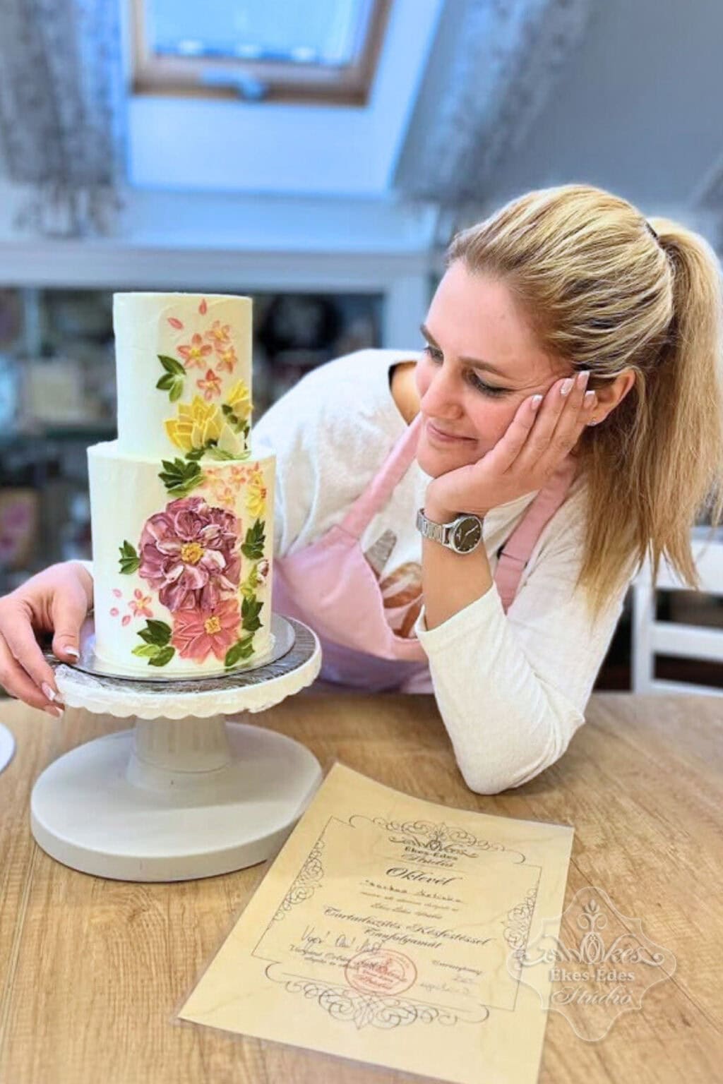 Tanfolyam végén a tanfolyam résztvevője büszkén és örömmel tekint az elkészült tortájára – Ékes-Édes Stúdió, csokoládés tortadíszítő tanfolyam