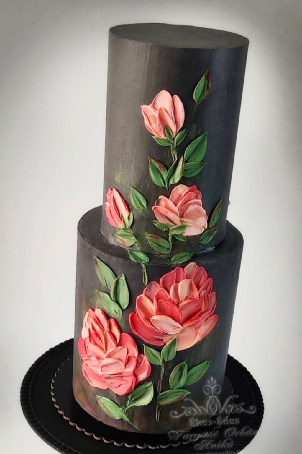 Dekoratív kétemeletes torta fekete háttérrel, csokoládéval festett virágmotívummal – Ékes-Édes Stúdió, tortadíszítő tanfolyam.