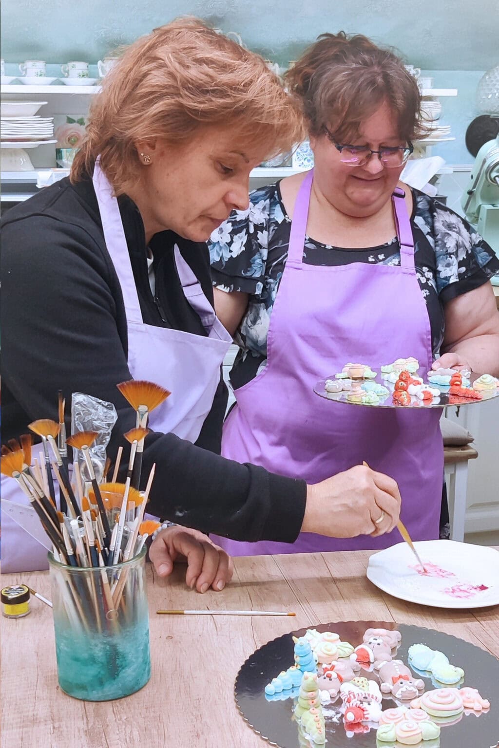 Ékes-Édes Stúdió pillecukor figurák tanfolyamán az utolsó simítások: a színes figurák kiegészítése festéssel két tanulóval a képen.