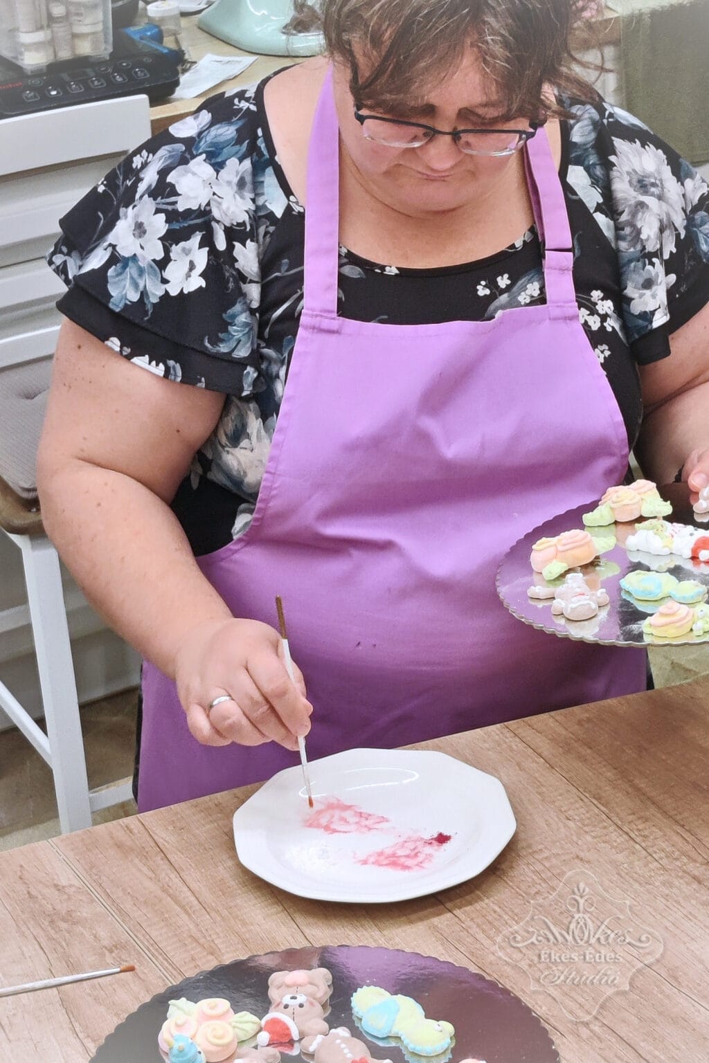 Dekoratív pillecukor figura készítés egy műhelyben, egy tanuló szemet fest a figuráknak.