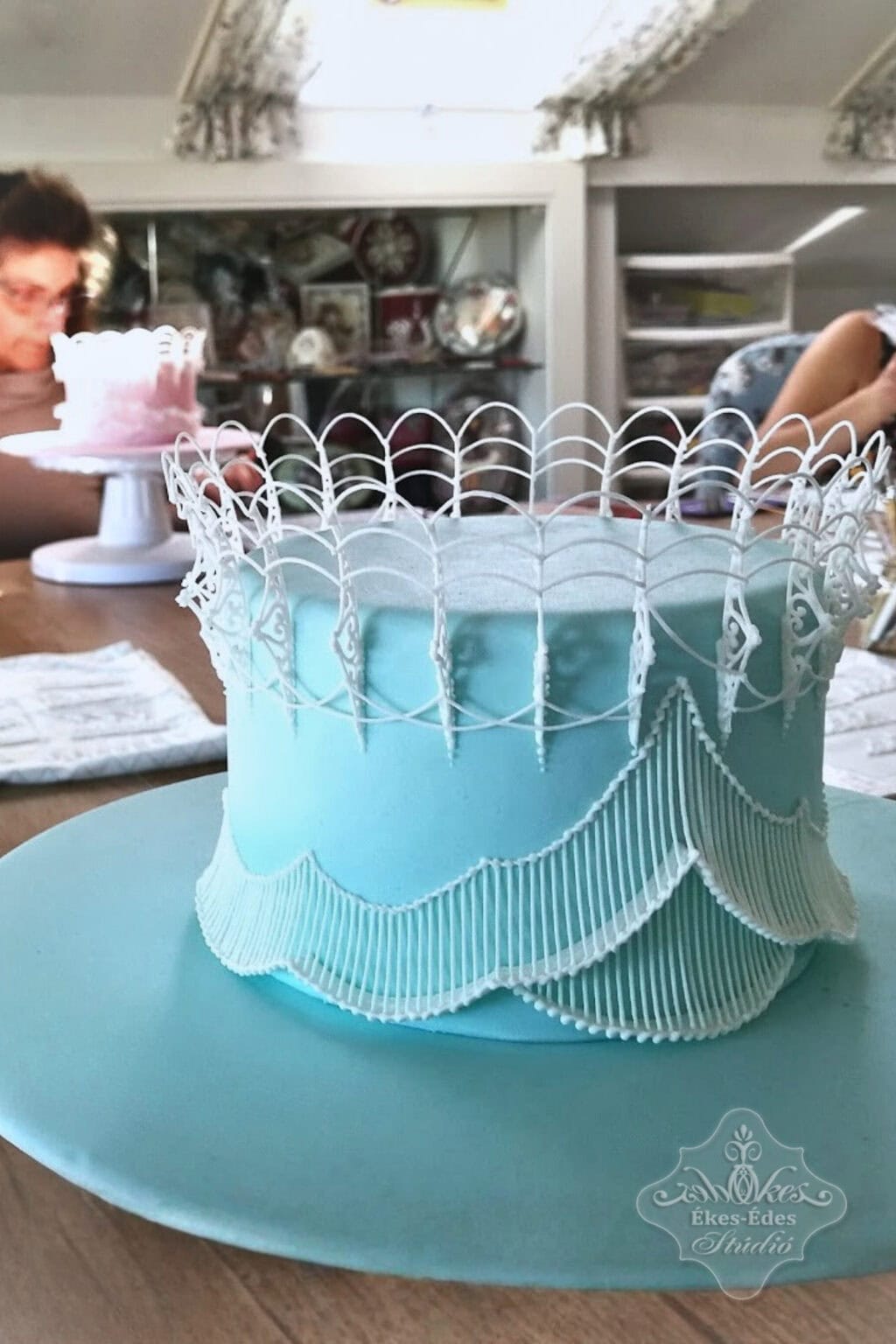 Royal icing string work, extension work és bridge technikák a közelről fotózott, kifinomultan díszített tortán.